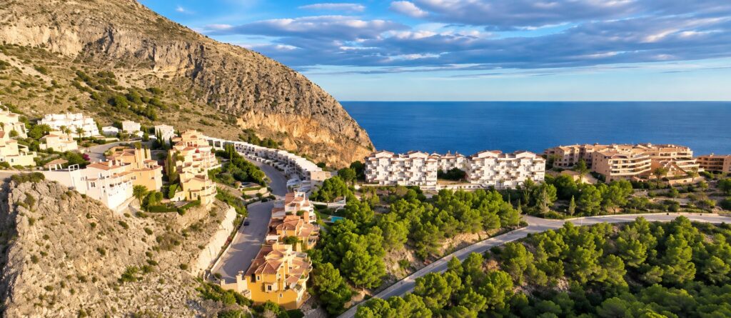Vista aérea de la ladera rocosa, edificios residenciales blancos y el mar